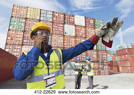 Worker using walkie-talkie near cargo containers View Large Photo Image Stock Photo - Worker using walkie-talkie near cargo containers. Fotosearch
