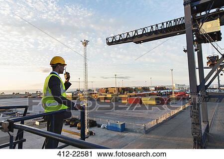Worker using walkie-talkie near crane View Large Photo Image Stock Image - Worker using walkie-talkie near crane. Fotosearch