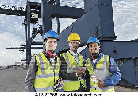 Workers and businessman smiling near cargo crane View Large Photo Image Stock Photo - Workers and businessman smiling near cargo crane. Fotosearch