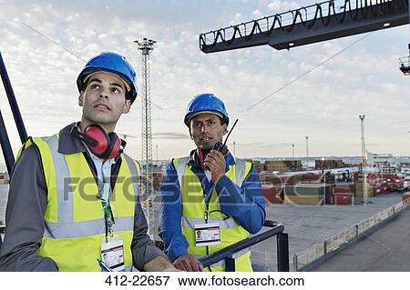 Stock Photo - Workers standing on cargo crane. Fotosearch