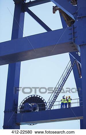Stock Image - Workers standing on crane. Fotosearch