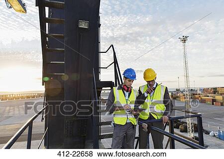 Workers using walkie-talkie on cargo crane View Large Photo Image Stock Photo - Workers using walkie-talkie on cargo crane. Fotosearch