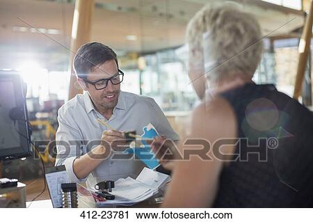 Stock Image - Business people eating at office desk. Fotosearch