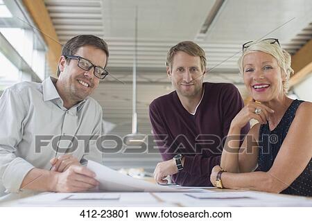 Stock Image - Business people smiling in office meeting. Fotosearch