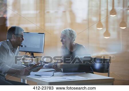 Stock Image - Business people talking at office desk. Fotosearch