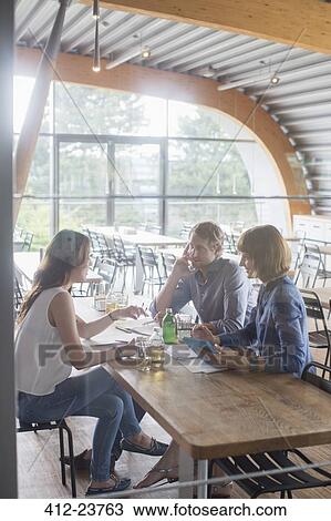 Stock Image - Business people talking in cafeteria. Fotosearch