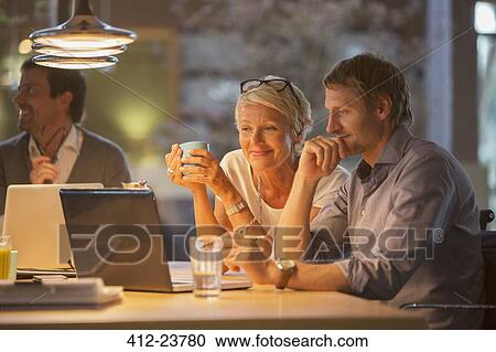 Stock Image - Business people using laptop in office meeting. Fotosearch