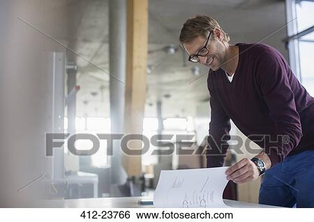 Stock Photograph - Businessman reading paperwork in office. Fotosearch