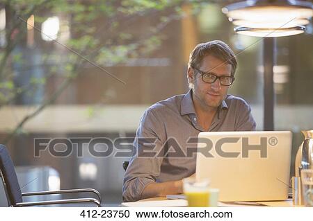 Stock Image - Businessman working at laptop in office. Fotosearch