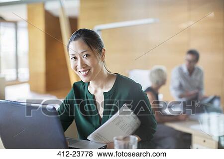 Stock Photo - Businesswoman smiling with laptop in office. Fotosearch