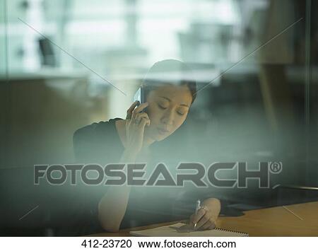 Businesswoman talking on cell phone in office View Large Photo Image Stock Image - Businesswoman talking on cell phone in office. Fotosearch