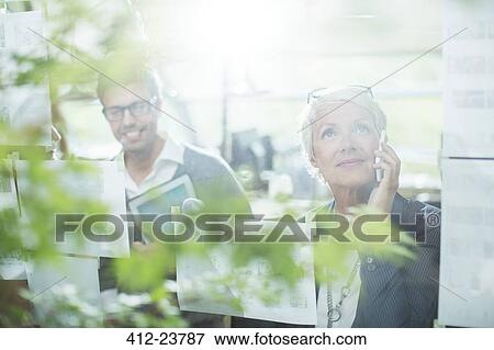 Stock Photo - Businesswoman talking on cell phone in office. Fotosearch