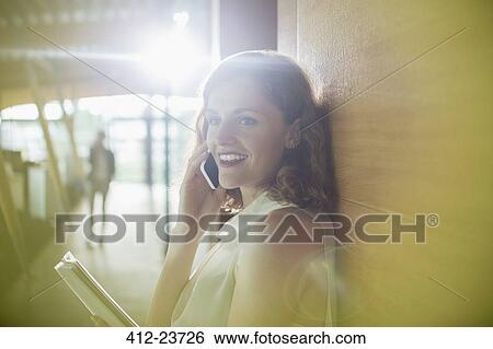 Stock Photograph - Businesswoman talking on cell phone in office. Fotosearch