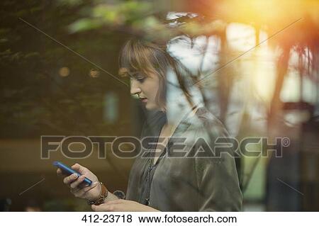 Stock Photo - Businesswoman using cell phone in office . Fotosearch