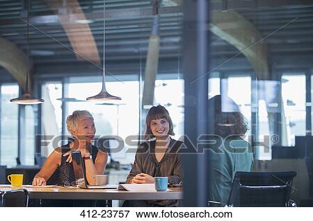 Stock Photo - Businesswomen talking in office meeting. Fotosearch