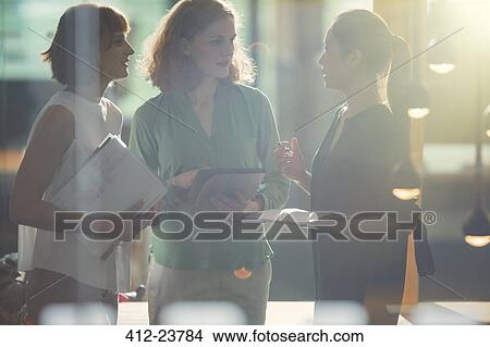 Businesswomen talking in office View Large Photo Image Picture - Businesswomen talking in office. Fotosearch