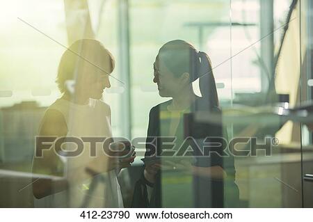 Businesswomen talking in office View Large Photo Image Stock Image - Businesswomen talking in office. Fotosearch