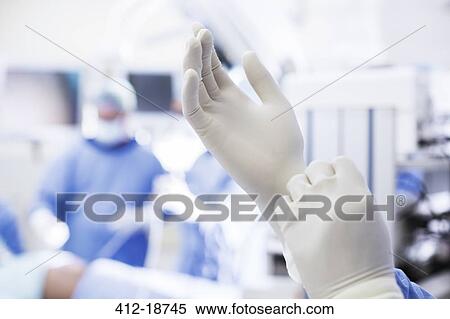Stock Photography - Close-up of surgeon putting on surgical gloves in operating theater. Fotosearch