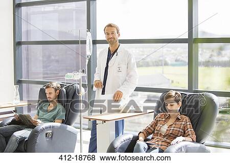 Doctor attending patients receiving intravenous infusion in hospital View Large Photo Image Stock Photo - Doctor attending patients receiving intravenous infusion in hospital. Fotosearch
