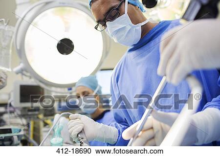 Doctor performing surgery in operating theater View Large Photo Image Stock Image - Doctor performing surgery in operating theater. Fotosearch