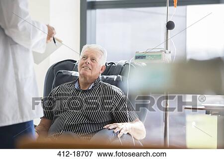 Doctor talking to patient receiving medical treatment in hospital ward View Large Photo Image Stock Photo - Doctor talking to patient receiving medical treatment in hospital ward. Fotosearch