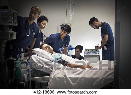 Stock Photograph - Group of doctors caring for patient in hospital ward. Fotosearch