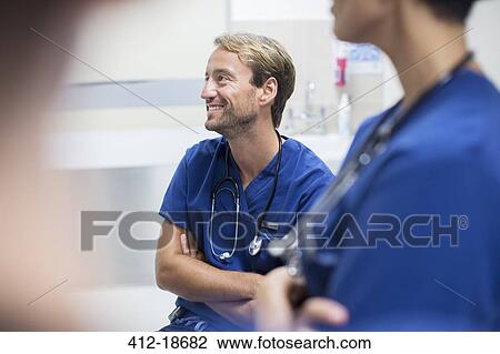 Mid adult doctor with crossed arms sitting and smiling in hospital ward View Large Photo Image Stock Image - Mid adult doctor with crossed arms sitting and smiling in hospital ward. Fotosearch