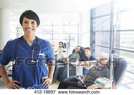 Portrait of doctor with patients receiving medical treatment in background View Large Photo Image Stock Photo - Portrait of doctor with patients receiving medical treatment in background. Fotosearch
