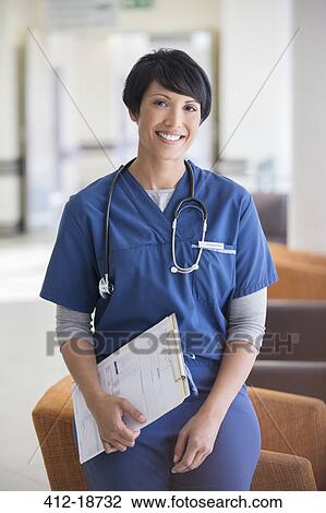 Portrait of female doctor holding clipboard in hospital View Large Photo Image Stock Image - Portrait of female doctor holding clipboard in hospital. Fotosearch