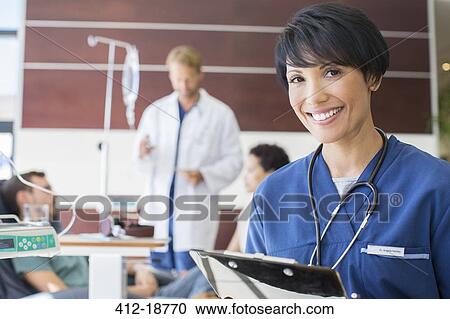 Portrait of female doctor holding clipboard in hospital View Large Photo Image Stock Image - Portrait of female doctor holding clipboard in hospital. Fotosearch