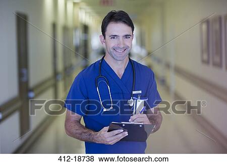 Portrait of male doctor holding clipboard in hospital corridor View Large Photo Image Stock Photo - Portrait of male doctor holding clipboard in hospital corridor. Fotosearch