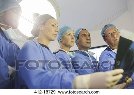 Stock Photo - Surgeons looking at x-ray during surgery in operating theater. Fotosearch