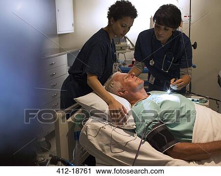 Two doctors attending patient in hospital ward View Large Photo Image Stock Image - Two doctors attending patient in hospital ward. Fotosearch