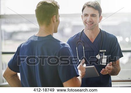 Two doctors talking, one holding tablet pc View Large Photo Image Stock Photo - Two doctors talking, one holding tablet pc. Fotosearch