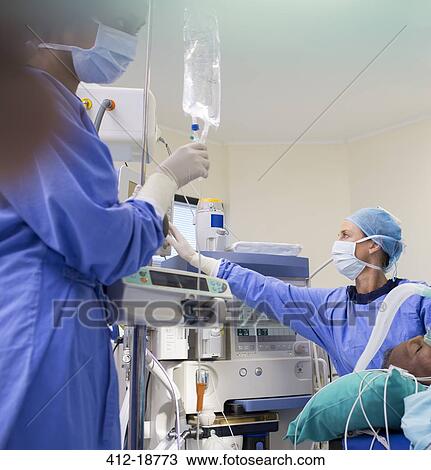 Stock Image - Two surgeons preparing medical equipment for operation. Fotosearch