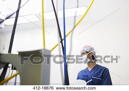 Stock Photograph - Young female nurse controlling medical equipment during surgery . Fotosearch