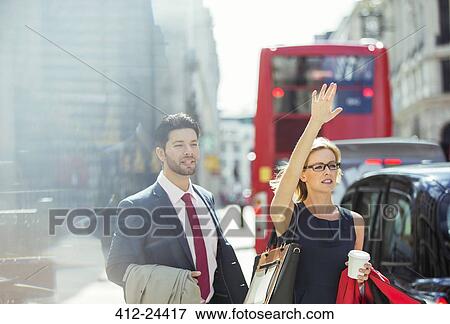 Stock Photo - Business people hailing taxi in city. Fotosearch