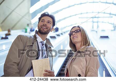 Stock Photo - Business people riding escalator. Fotosearch
