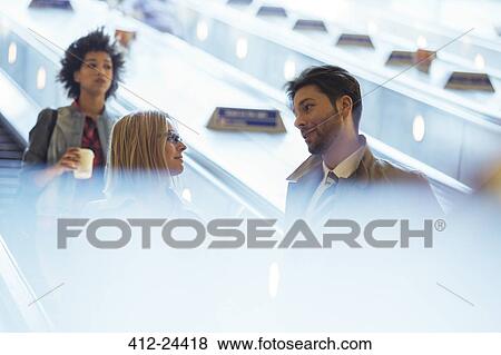 Stock Photo - Business people talking on escalator. Fotosearch