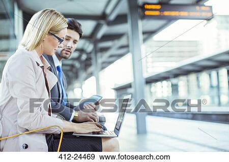 Stock Photo - Business people using laptop at train station. Fotosearch