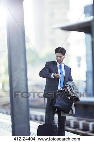 Picture - Businessman checking his watch in train station. Fotosearch