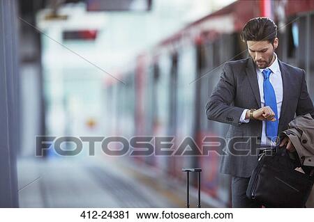 Businessman checking his watch in train station View Large Photo Image Stock Image - Businessman checking his watch in train station. Fotosearch