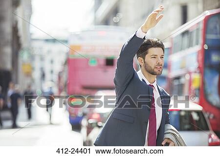 Stock Image - Businessman hailing taxi in city. Fotosearch