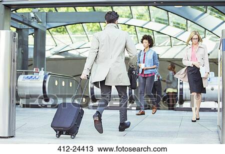 Businessman pulling luggage near escalators View Large Photo Image Stock Image - Businessman pulling luggage near escalators. Fotosearch