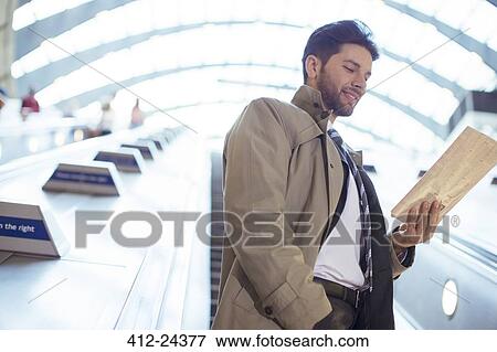 Stock Photo - Businessman reading newspaper on escalator. Fotosearch