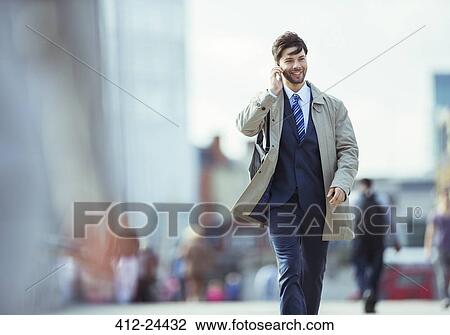 Stock Image - Businessman talking on cell phone outdoors. Fotosearch