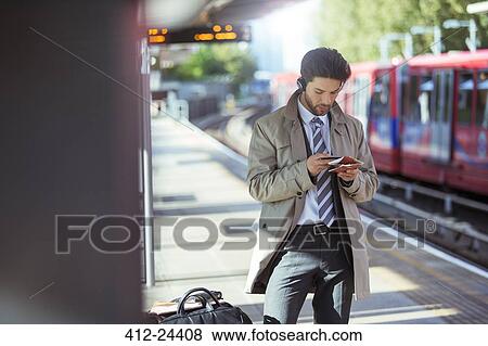 Businessman using cell phone in train station View Large Photo Image Stock Photo - Businessman using cell phone in train station. Fotosearch