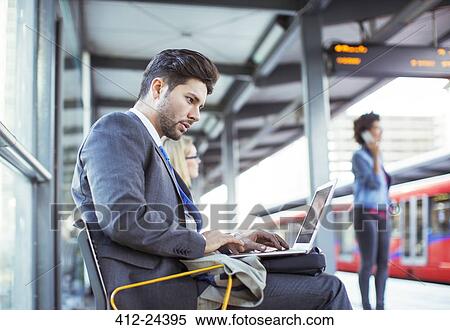Businessman using laptop at train station View Large Photo Image Stock Photography - Businessman using laptop at train station. Fotosearch