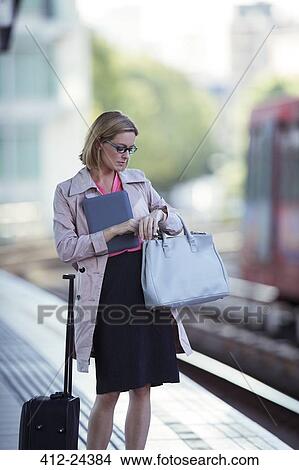 Picture - Businesswoman checking her watch at train station. Fotosearch