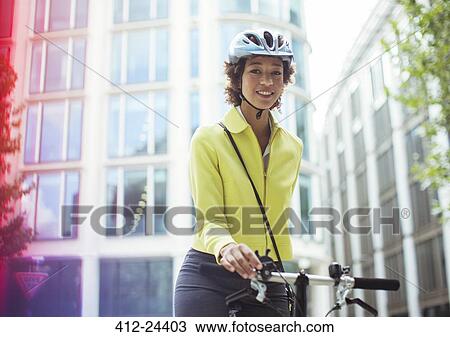 Stock Image - Businesswoman pushing bicycle in city. Fotosearch